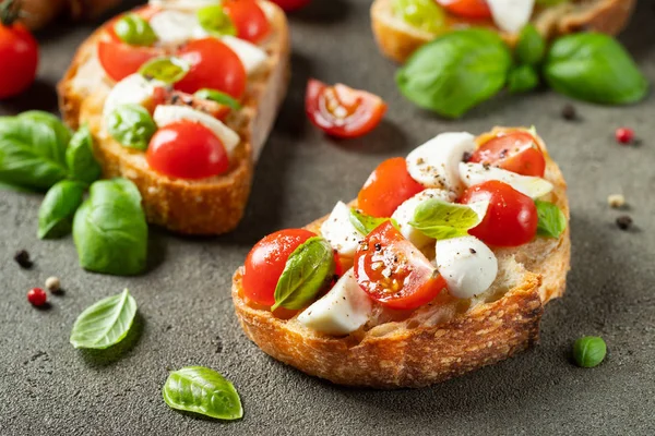 Bruschetta con tomates, queso mozzarella y albahaca sobre una vieja mesa rústica. Aperitivo o merienda tradicional italiana, antipasto — Foto de Stock