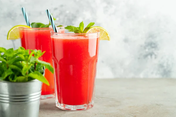 Watermelon slushie with lime and mint, summer refreshing drink in tall glasses on a light blue background. Sweet cold smoothie with copy space — Stock Photo, Image