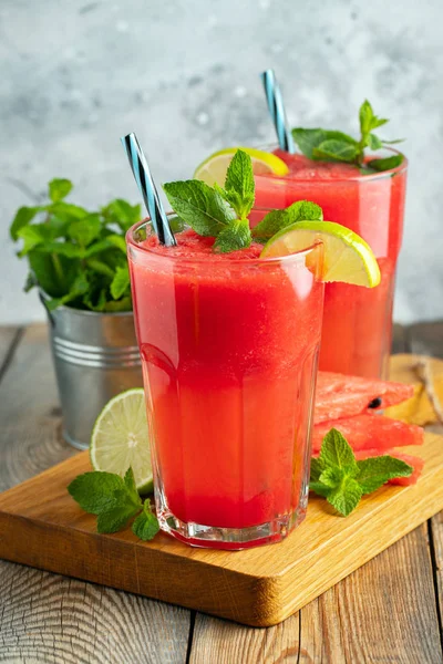 Watermeloen slushie met limoen en Mint, zomer verfrissend drankje in hoge glazen op een licht blauwe achtergrond. Zoete koude smoothie — Stockfoto