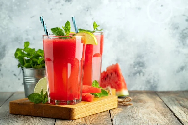 Watermelon slushie with lime and mint, summer refreshing drink in tall glasses on a light blue background. Sweet cold smoothie with copy space — Stock Photo, Image