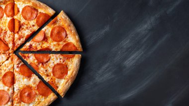 Lezzetli biberli pizza ve siyah beton arka planda domates fesleğeni. Acı biberli pizzanın en iyi manzarası. Metin için kopyalama alanı ile. Düz yatıyordu. Pankart