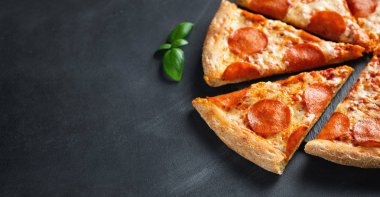 Siyah beton arka plan üzerinde lezzetli pepperoni pizza. Acı biberli pizzanın en iyi görünümü. Metin için kopyalama alanı ile. Düz yatıyordu. Afiş