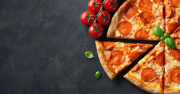 Sabrosa pizza de pepperoni e ingredientes de cocina tomates albahaca sobre fondo de hormigón negro. Vista superior de la pizza de pepperoni picante. Con espacio de copia para texto. Acostado. Banner — Foto de Stock