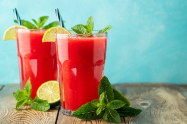 Kireç ve nane ile Karpuz slushie, açık mavi arka plan üzerinde uzun boylu gözlük yaz ferahlatıcı içecek. Kopya alanı ile tatlı soğuk smoothie