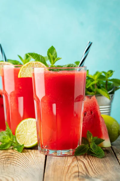 Watermeloen slushie met limoen en Mint, zomer verfrissend drankje in hoge glazen op een licht blauwe achtergrond. Zoete koude smoothie — Stockfoto