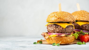 Hafif beton arka planda sığır eti, pastırma, peynir, marul ve domates ev yapımı lezzetli burger bir dizi. Yağ sağlıksız gıda yakın çekim. Kopyalama alanı ile