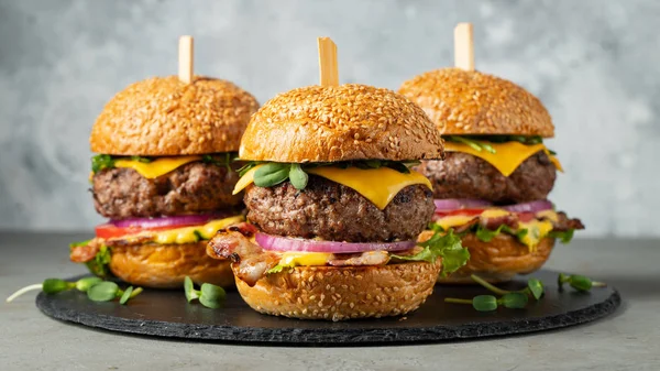 一套自制的美味汉堡，包括牛肉、培根、奶酪、生菜和西红柿，背景是清淡的混凝土背景。脂肪不健康食品特写 — 图库照片