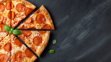 Siyah beton arka plan üzerinde lezzetli pepperoni pizza. Acı biberli pizzanın en iyi görünümü. Metin için kopyalama alanı ile. Düz yatıyordu. Afiş