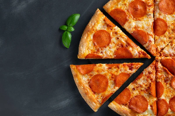 Leckere Pfefferoni-Pizza und Kochzutaten Tomaten Basilikum auf schwarzem Betongrund. Blick von oben auf die Chili-Pizza. Mit Kopierraum für Text. Flache Lage — Stockfoto