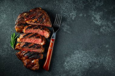 Dilimlenmiş biftek ribeye, biber, sarımsak, tuz ve kekik ile ızgara koyu taş arka plan üzerinde. Üst te. Düz yatıyordu