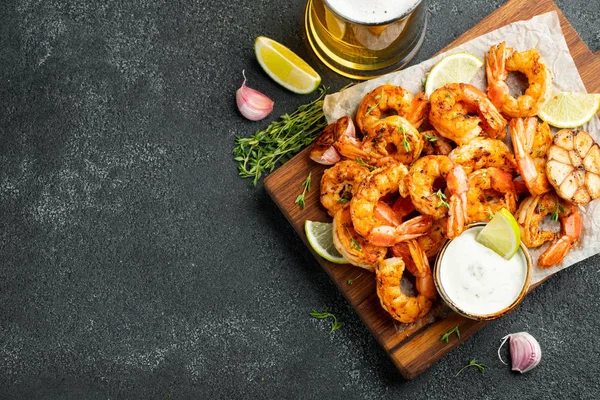 Gamberetti alla griglia o gamberetti serviti con lime, aglio e salsa bianca su uno sfondo di cemento scuro. Frutti di mare. Vista dall'alto con spazio di copia. Posa piatta — Foto Stock