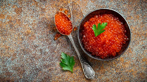 Delicious red caviar in black bowl on a dark concrete background. Top view with copy space. Flat lay — Stock Photo, Image