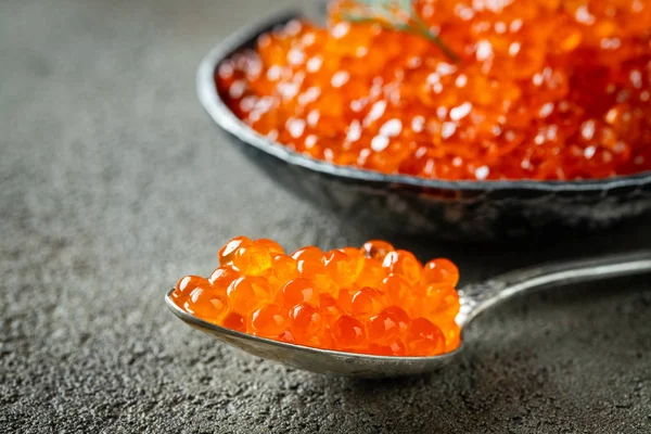 Close-up delicious red caviar in a spoon on a dark concrete back — Stock Photo, Image
