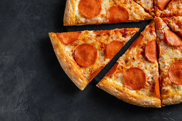 Leckere Pfefferoni-Pizza und Kochzutaten Tomaten Basilikum auf schwarzem Betongrund. Blick von oben auf Chili-Pizza. flache Lage — Stockfoto