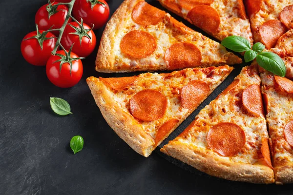 Leckere Pfefferoni-Pizza und Kochzutaten Tomaten Basilikum auf schwarzem Betongrund. Blick von oben auf Chili-Pizza. flache Lage — Stockfoto