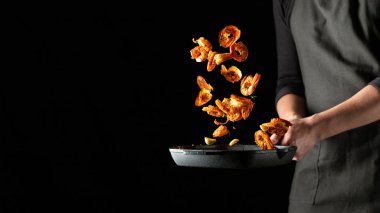 Profesyonel şef baharatile karides veya langoustines hazırlar. Akdeniz deniz ürünleri, koyu bir arka plan üzerinde sağlıklı vejetaryen gıda pişirme. Metin için kopyalama alanı ile