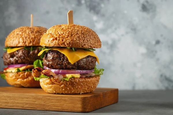 Um conjunto de deliciosos hambúrgueres caseiros de carne bovina, bacon, queijo, alface e tomate em um fundo de concreto leve. Gordura comida não saudável close-up. Com espaço de cópia — Fotografia de Stock