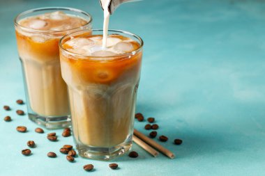 Büyük bardakta buzlu kahve, krema dökülmüş ve kahve çekirdekleri arka planda. Borularla soğuk yaz içkisi. Kopyalama alanı ile