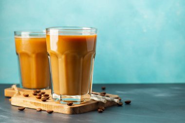 Büyük bardakta buzlu kahve, krema dökülmüş ve kahve çekirdekleri arka planda. Borularla soğuk yaz içkisi. Kopyalama alanı ile