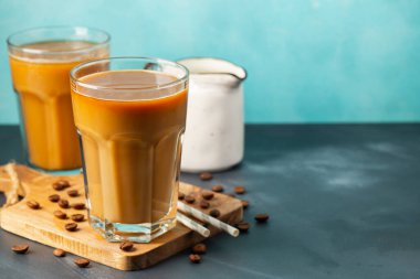 Büyük bardakta buzlu kahve, krema dökülmüş ve kahve çekirdekleri arka planda. Borularla soğuk yaz içkisi. Kopyalama alanı ile