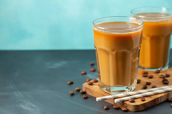 Παγωμένος καφές σε ψηλό ποτήρι με κρέμα γάλακτος και κόκκους καφέ σε ελαφρύ πέτρινο φόντο. Κρύο καλοκαιρινό ποτό με σωλήνες. Με χώρο αντιγραφής — Φωτογραφία Αρχείου