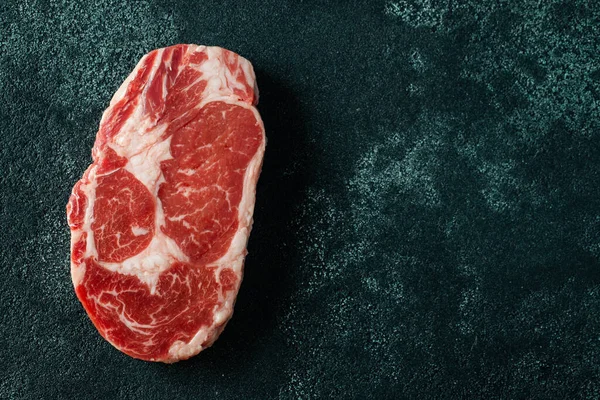 Carne fresca cruda Ribeye Steak y condimento sobre fondo oscuro. Vista superior con espacio de copia. Puesta plana — Foto de Stock