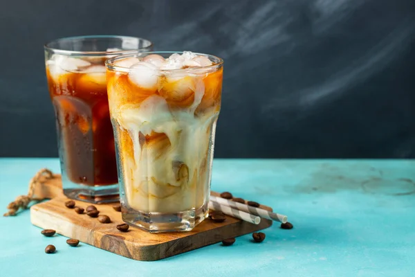 Es kopi dalam gelas tinggi dengan krim dituangkan di atas dan biji kopi pada latar belakang batu cahaya. Minuman musim panas yang dingin dengan tabung. Dengan ruang fotokopi — Stok Foto