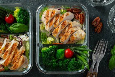 Taze fasulye, tavuk göğsü ve brokoli ile sağlıklı yemek hazırlama kapları. Koyu beton arka planda, beslenme çantasında Keto diyeti için bir set yiyecek. Üst görünüm.