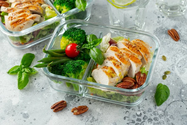 Healthy meal prep containers with green beans, chicken breast and broccoli. A set of food for keto diet in lunchbox on a light concrete background. Top view.