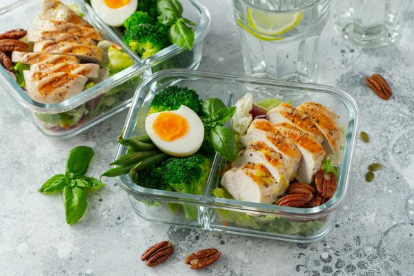 Healthy meal prep containers with green beans, chicken breast and broccoli. A set of food for keto diet in lunchbox on a light concrete background. Top view.