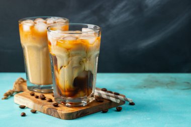 Büyük bardakta buzlu kahve, krema dökülmüş ve kahve çekirdekleri arka planda. Borularla soğuk yaz içkisi. Kopyalama alanı ile