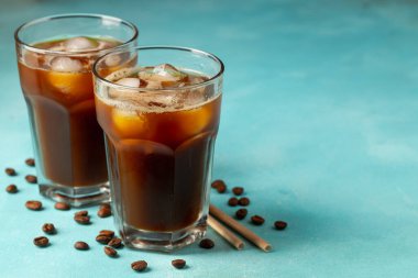 Büyük bardakta buzlu kahve, krema dökülmüş ve kahve çekirdekleri arka planda. Borularla soğuk yaz içkisi. Kopyalama alanı ile