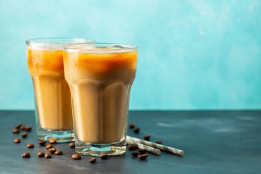 Büyük bardakta buzlu kahve, krema dökülmüş ve kahve çekirdekleri arka planda. Borularla soğuk yaz içkisi. Kopyalama alanı ile