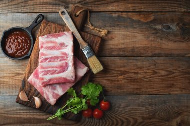 Baharatlı çiğ domuz pirzolası, siyah ahşap arka planda tuz ve biberiye. Kopyalama alanı olan üst görünüm.