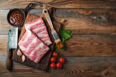 Baharatlı çiğ domuz pirzolası, siyah ahşap arka planda tuz ve biberiye. Kopyalama alanı olan üst görünüm.