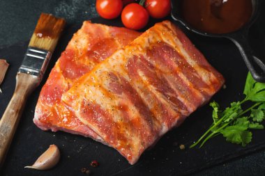 Barbekü, çiğ domuz pirzolası ve barbekü sosu hazır. Siyah arka plan. Üst görünüm.