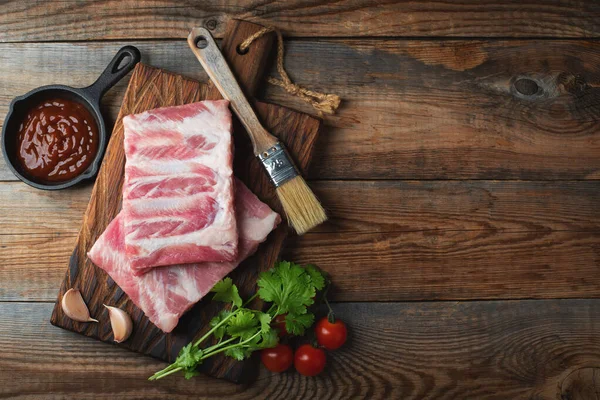 Baharatlı çiğ domuz pirzolası, siyah ahşap arka planda tuz ve biberiye. Kopyalama alanı olan üst görünüm.