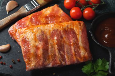 Barbekü, çiğ domuz pirzolası ve barbekü sosu hazır. Siyah arka plan. Üst görünüm.