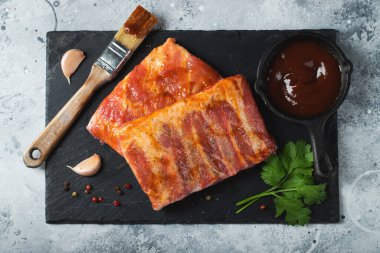 Barbekü, çiğ domuz pirzolası ve barbekü sosu hazır. Siyah arka plan. Üst görünüm.