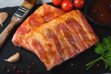 Barbekü, çiğ domuz pirzolası ve barbekü sosu hazır. Siyah arka plan. Üst görünüm.