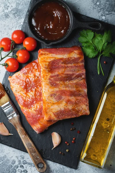 Barbekü, çiğ domuz pirzolası ve barbekü sosu hazır. Siyah arka plan. Üst görünüm.