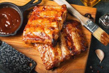 Baharatlı, ızgara pirzola. Barbekü, acı biber ve taze domatesle servis edilir. Eski bir ahşap kesim tahtasının üzerinde.