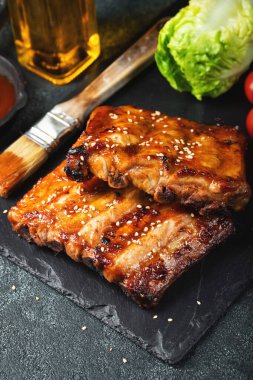 Barbekü domuz pirzolası ve siyah arka planda sıcak bal biberli terbiye..