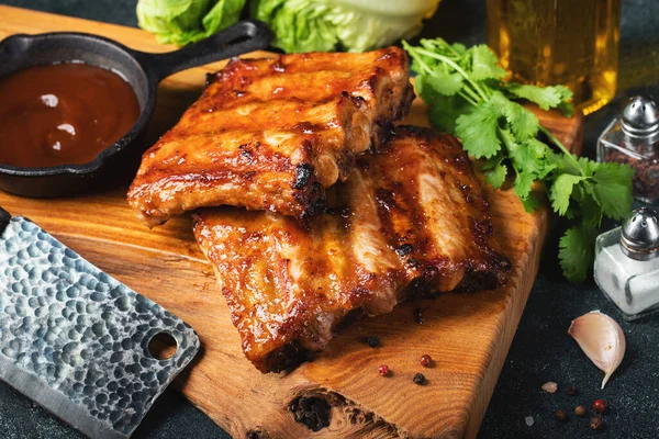 Baharatlı, ızgara pirzola. Barbekü, acı biber ve taze domatesle servis edilir. Eski bir ahşap kesim tahtasının üzerinde.