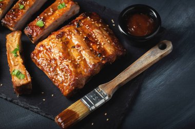 Barbekü domuz pirzolası ve siyah arka planda sıcak bal biberli terbiye..