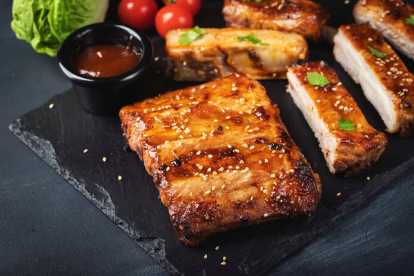 Barbekü domuz pirzolası ve siyah arka planda sıcak bal biberli terbiye..