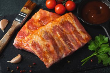 Barbekü, çiğ domuz pirzolası ve barbekü sosu hazır. Siyah arka plan. Üst görünüm.