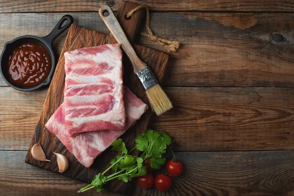 Baharatlı çiğ domuz pirzolası, siyah ahşap arka planda tuz ve biberiye. Kopyalama alanı olan üst görünüm.