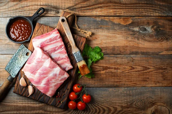 Baharatlı çiğ domuz pirzolası, siyah ahşap arka planda tuz ve biberiye. Kopyalama alanı olan üst görünüm.