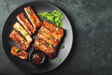 Barbekü soslu bir tabakta servis edilen sıcak ızgara pirzola. Üst Manzara. Boşluğu kopyala.